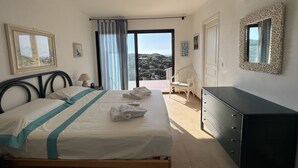 A bedroom with a bed, a dresser, a chair, and a view of the outdoors. - Villa “Le Terrazze” (Lumio)