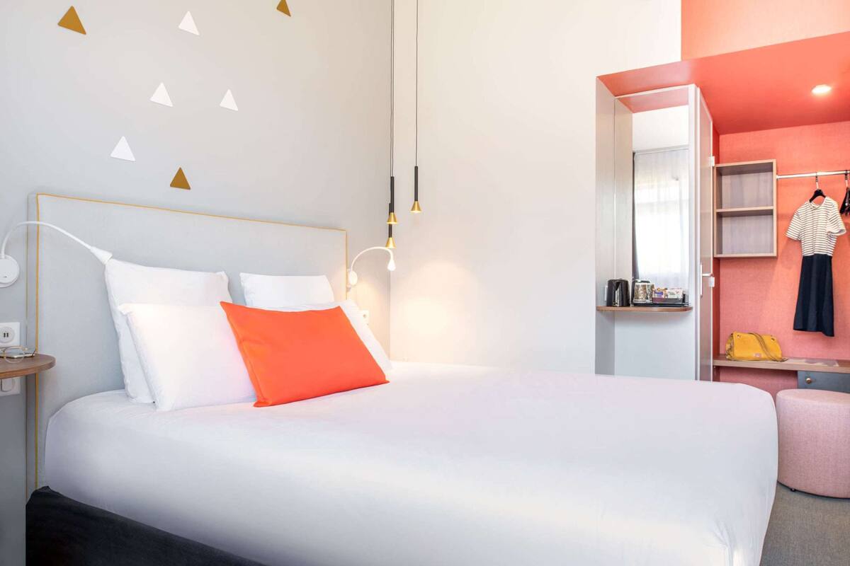 Une chambre d’hôtel moderne avec un grand lit, une table de chevet et une armoire.