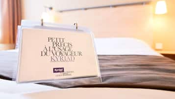 Una habitación de hotel con una cama, una mesita de noche y una lámpara de pared.