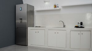 Una cocina moderna con un refrigerador de acero inoxidable, armarios blancos, un lavamanos integrado y una repisa sobre la encimera.