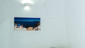 Una habitación con una pared blanca, un cuadro enmarco de un paisaje costero, una mesita con un cuenco y bancos acolchados verdes.