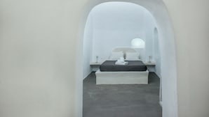 Un dormitorio minimalista con cama, mesita de noche y una ventana pequeña.