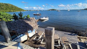 A wooden dock with lounge chairs and a thatched-roof structure, overlooking a calm body of water with several boats. - Waterfront villa 4 bedrooms, 3 bathrooms with pool, kayaks, high speed wifi (Cul-de-Sac)