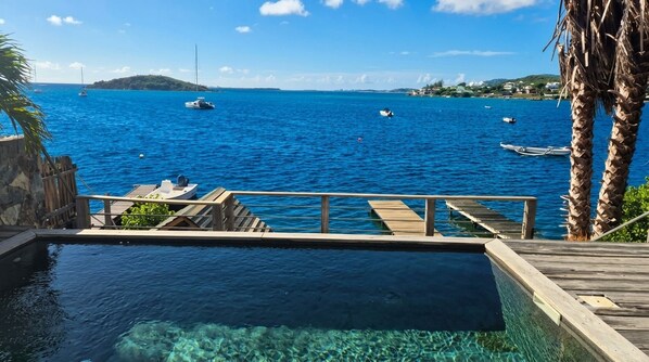Vista despejada de una piscina con muelle de madera y baranda de madera.