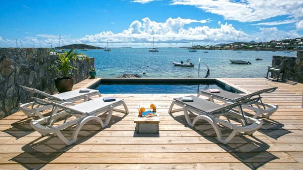 A wooden deck with a hot tub, lounge chairs, and a view of the sea with boats. - Waterfront villa 4 bedrooms, 3 bathrooms with pool, kayaks, high speed wifi (Cul-de-Sac)