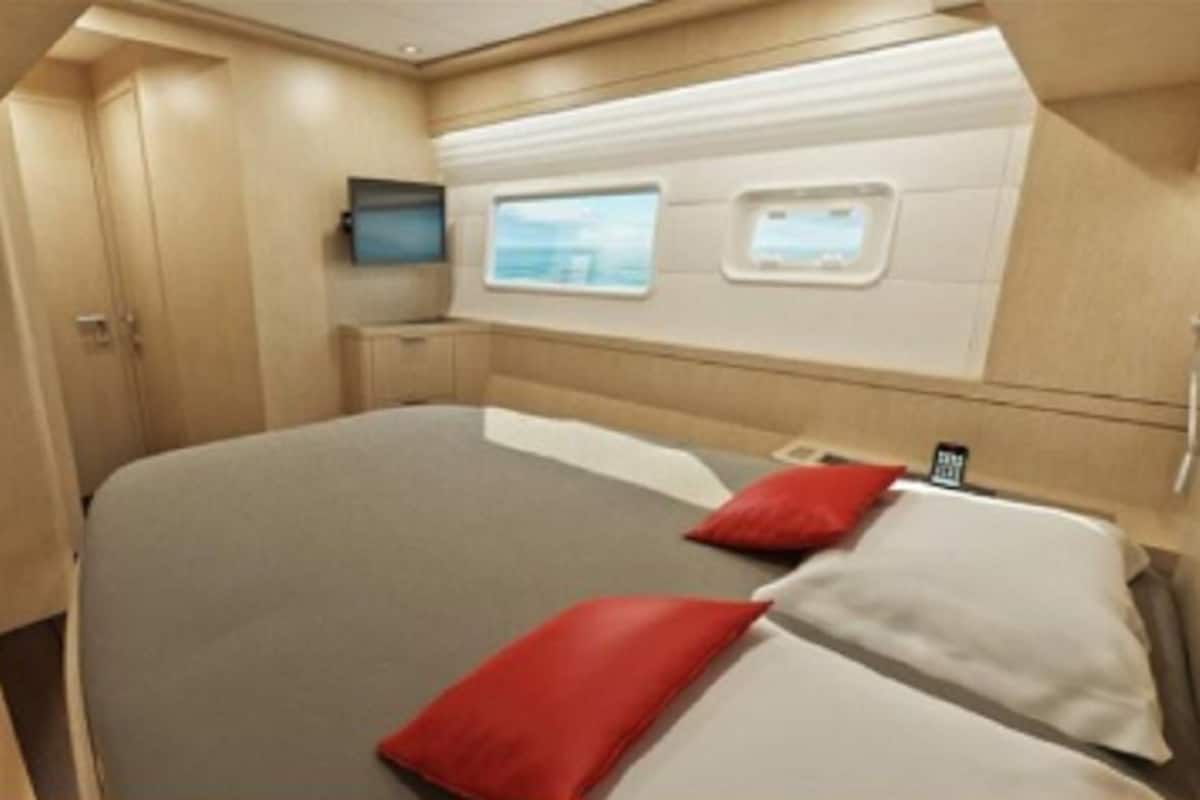 A bedroom with a bed, two pillows, a TV, and a window.
