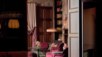 A dimly lit room with a chandelier, a bookshelf, and a seating area with a table and chairs.