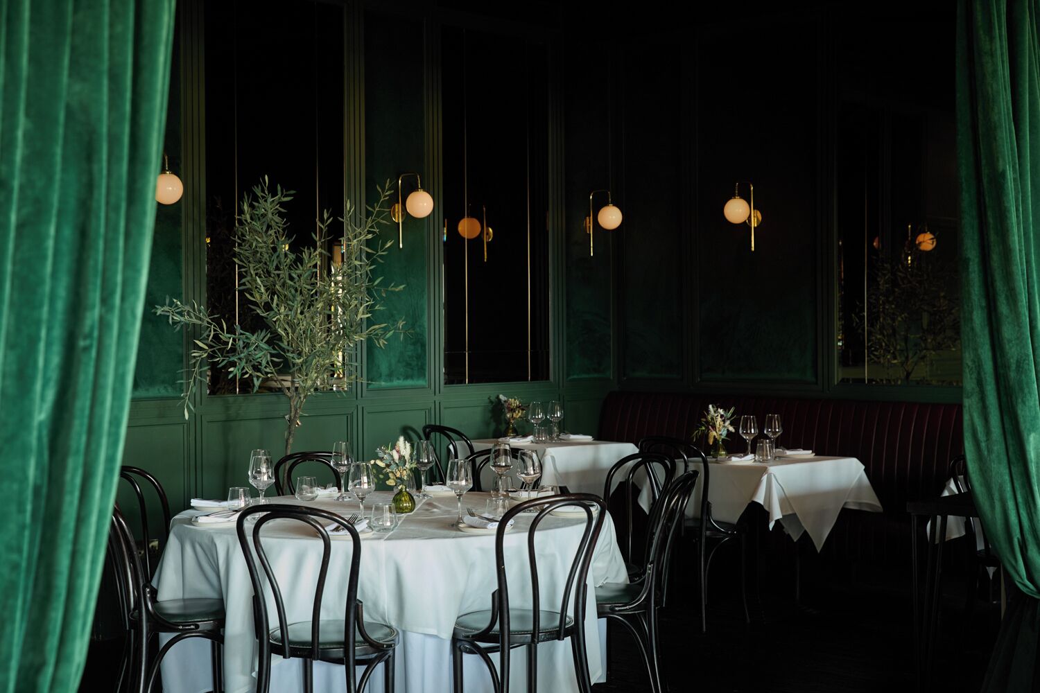 Ein Restaurant mit runden Tischen, Stühlen und hängenden Pendelleuchten.