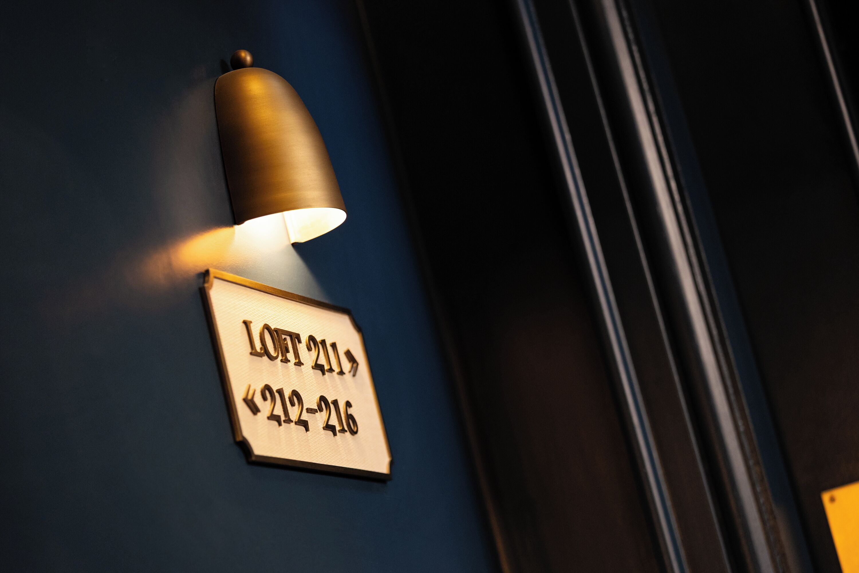 A wall-mounted light fixture with a sign indicating room number 211 and its range 212-216.