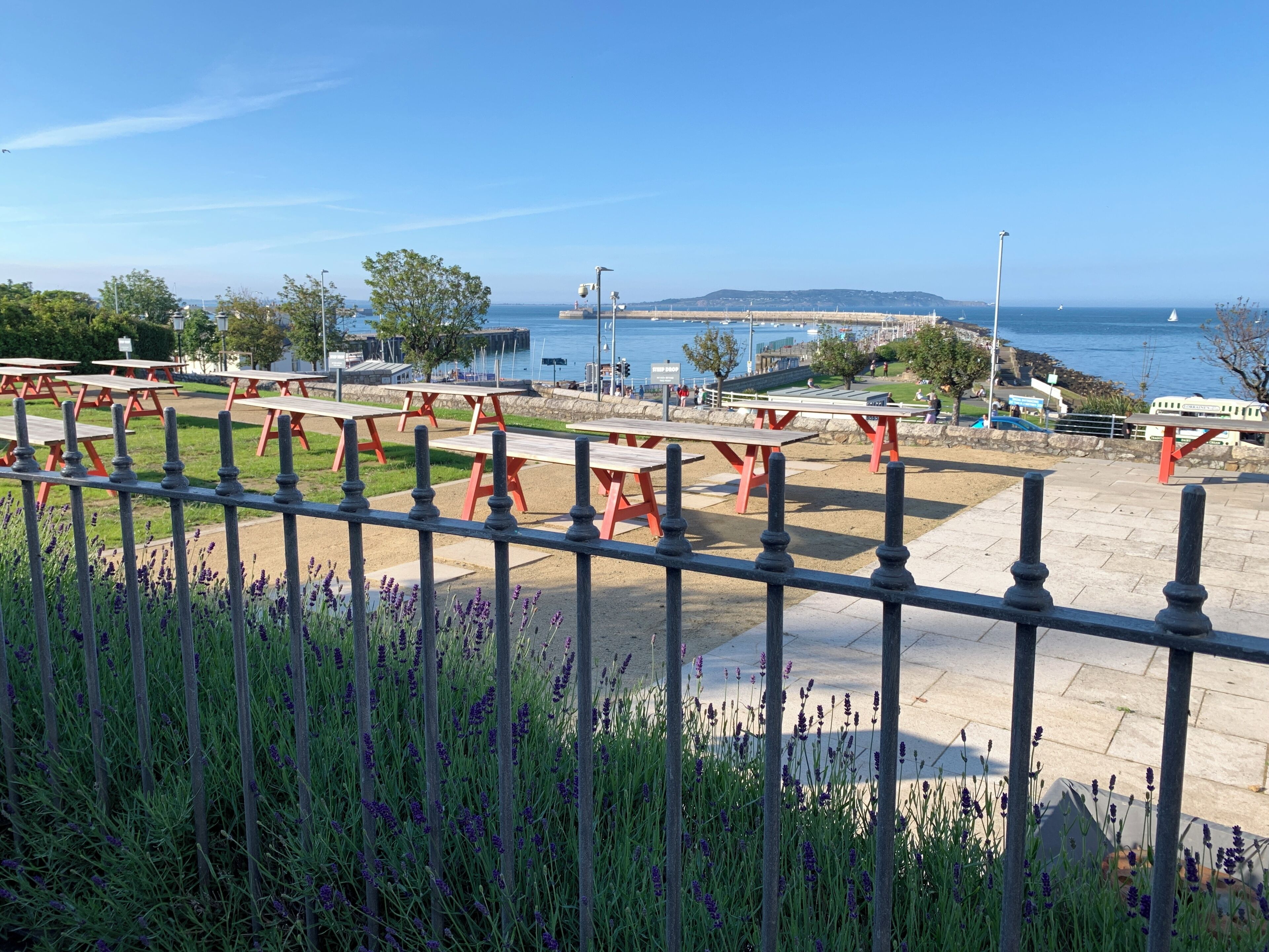 A coastal park with picnic tables and a view of the sea.