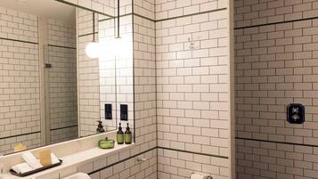 A modern bathroom with white subway tiles, a large mirror, a sink, and a toilet.