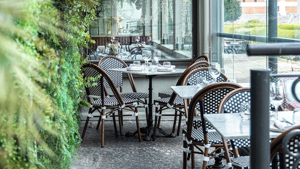 An outdoor dining area with tables and chairs, surrounded by lush greenery and a view of the street. - Haddington House Hotel (Dublin)