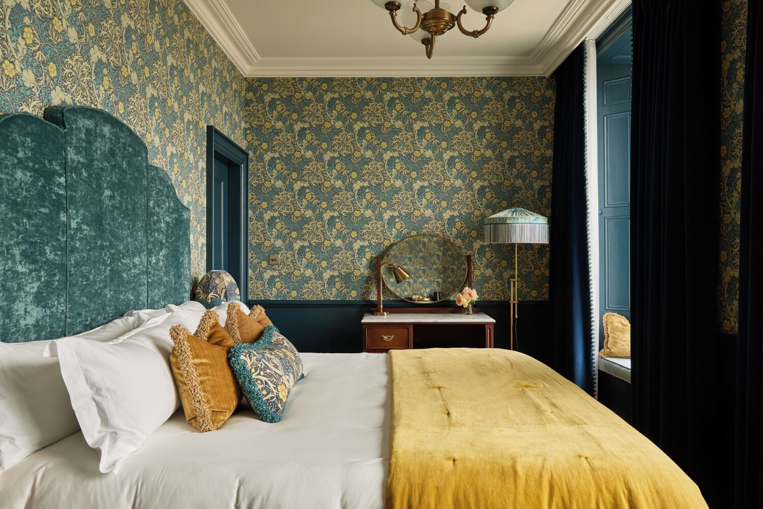 A bedroom with a bed, a dresser, a mirror, and a lamp.