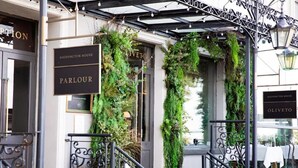 A hotel entrance with a wrought iron gate, a sign reading "HADDINGTON HOUSE PARLOUR," and lush greenery draped over the entrance. - Haddington House Hotel (Dublin)