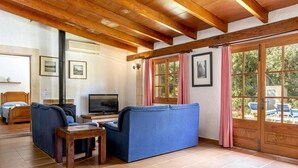 Uma sala de estar aconchegante com teto de madeira, um sofá, uma televisão e uma lareira.