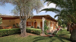 Um edifício tradicional em estilo mediterrâneo com um pátio, área de estar ao ar livre e paisagismo bem cuidado.
