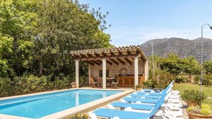 Piscina com espreguiçadeiras, pérgola e vista para montanhas.