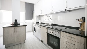A modern kitchen with white cabinets, a black countertop, and stainless steel appliances.