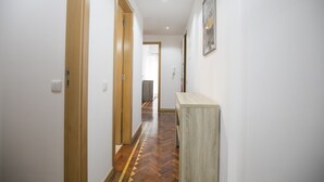 A hallway with wooden doors, a herringbone-patterned floor, and a light-colored console table.