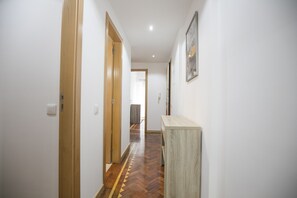 Un pasillo con puertas de madera, suelo con diseño de espiga y una consola de mesa clara.