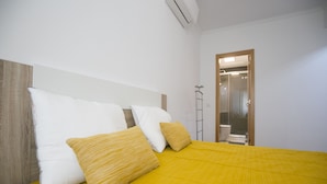 A hotel room with a bed, pillows, and a bathroom visible through an open door.