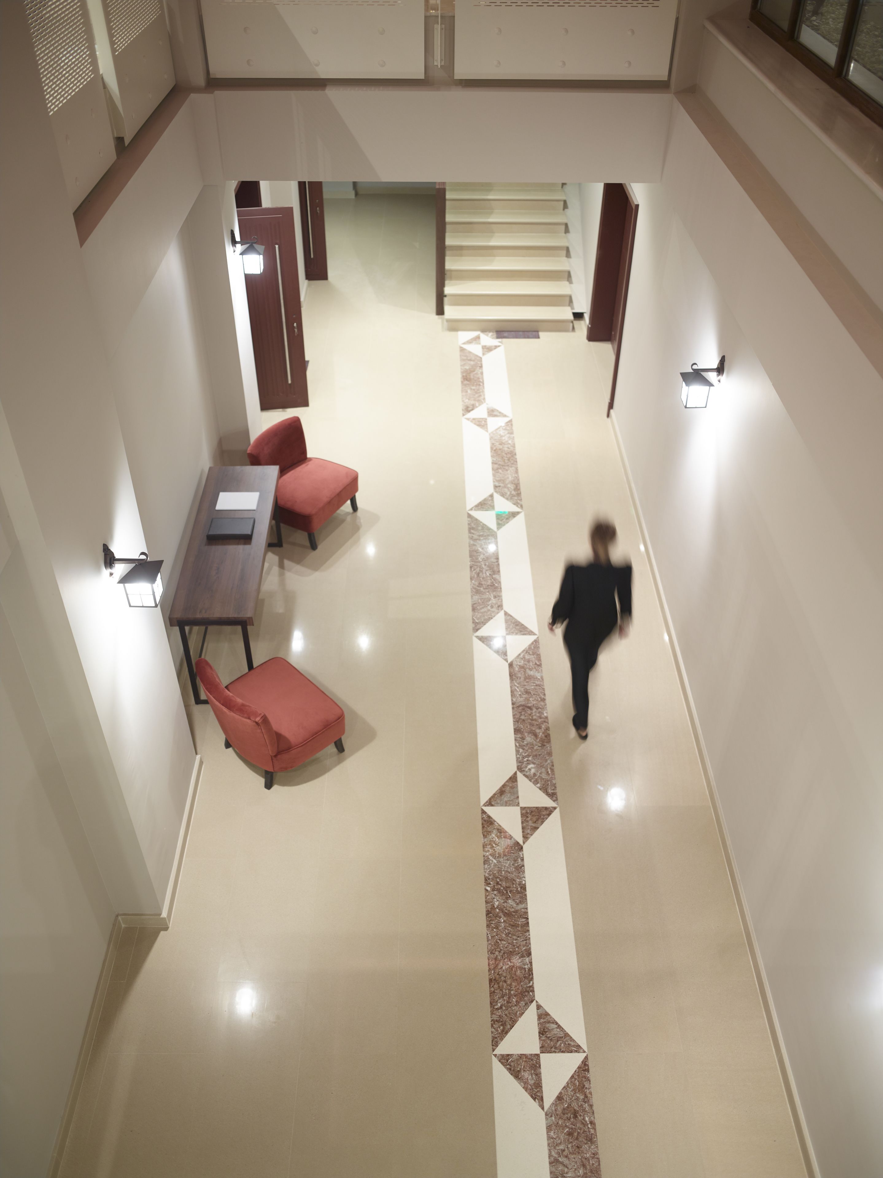 Amplio espacio interior con un pasillo central, una escalera y arreglos de asientos.