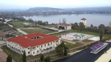 A large building with a red roof, a swimming pool, and a tennis court.
