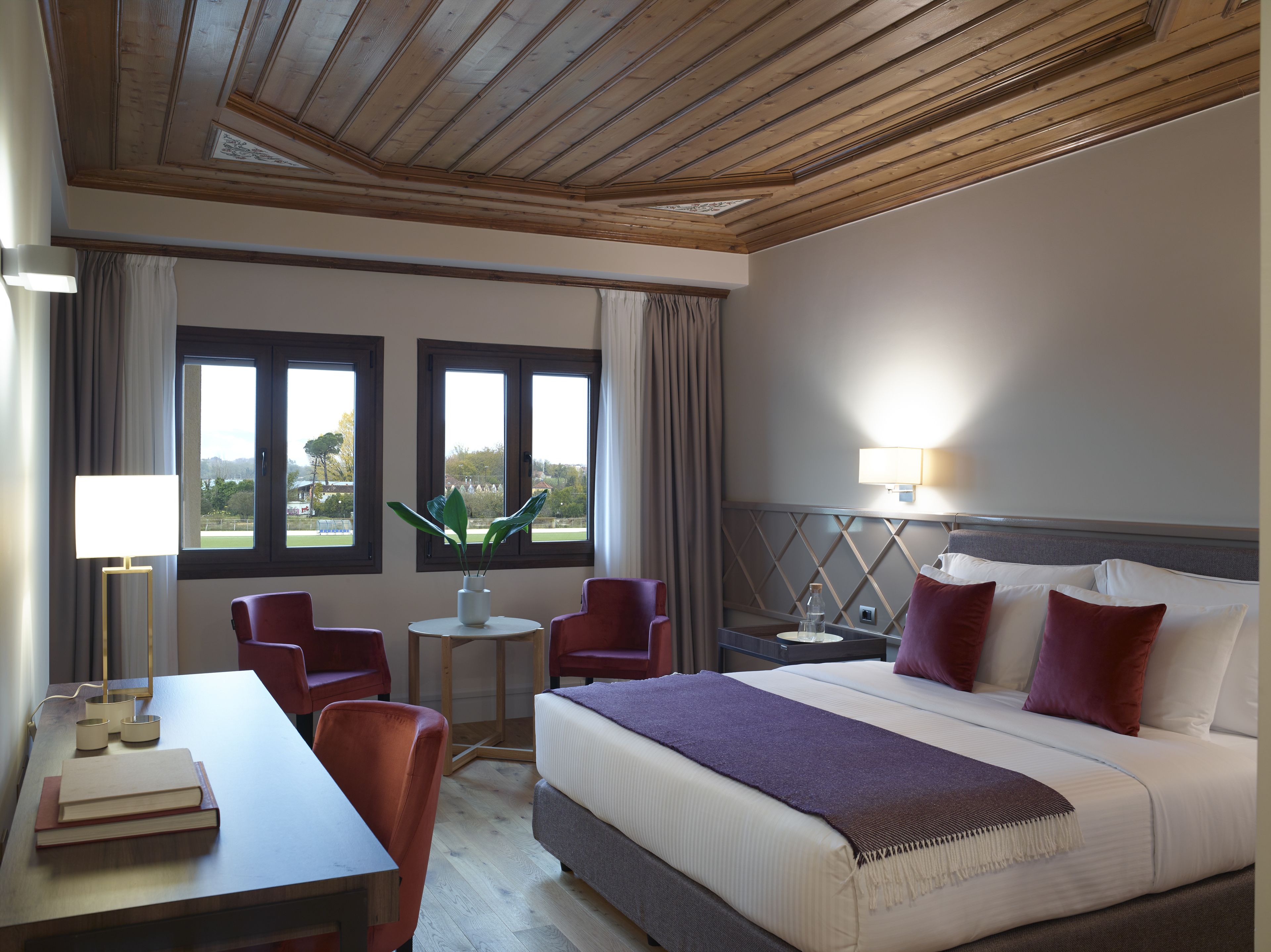 Een hotelkamer met een bed, twee stoelen, een tafeltje en een lamp.