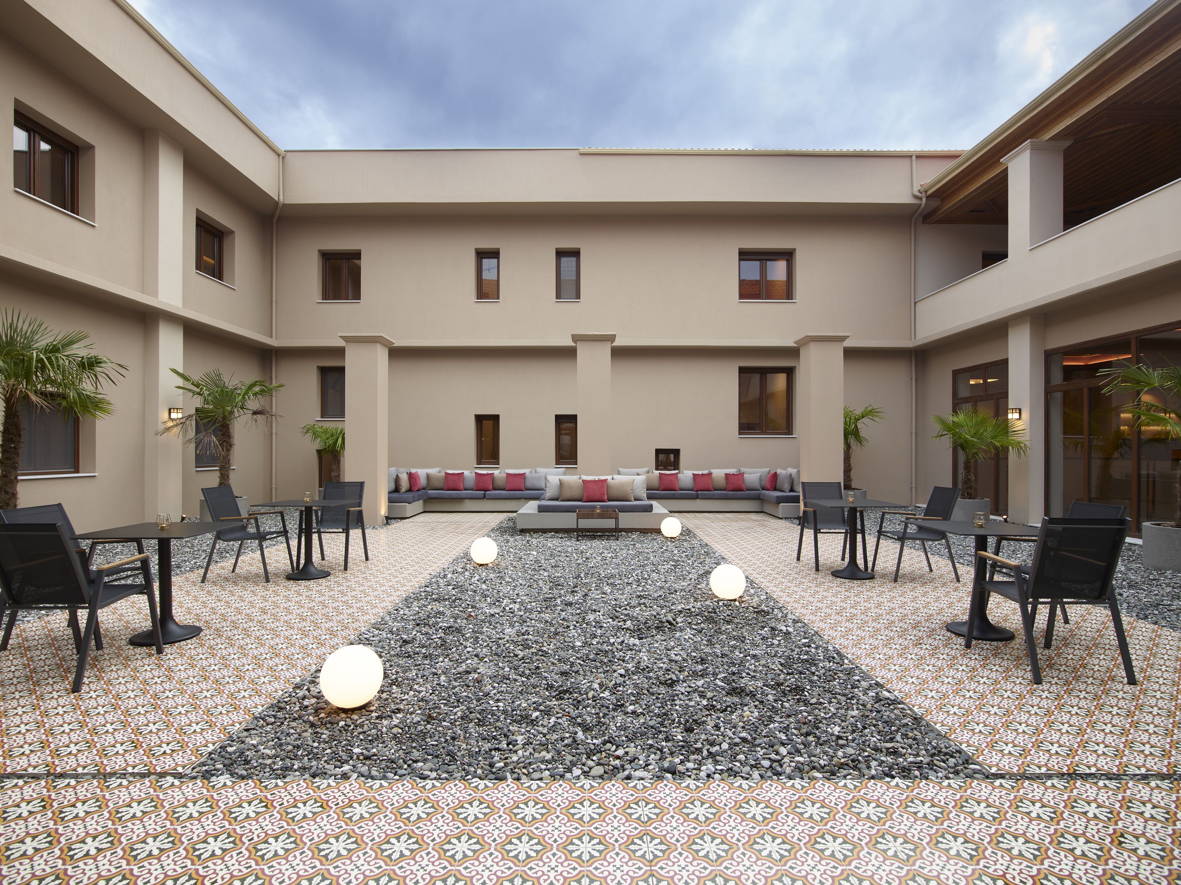 Un patio con zona de estar, mesas y plantas en macetas.