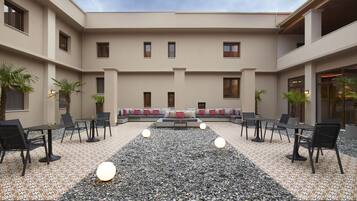 Un patio con zona de estar, mesas y plantas en macetas.
