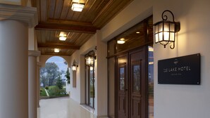 A hotel corridor with wooden ceiling beams, a sign reading "The Lake Hotel Ioannina", and a view of the outdoors. - The Lake Hotel (Ioannina)