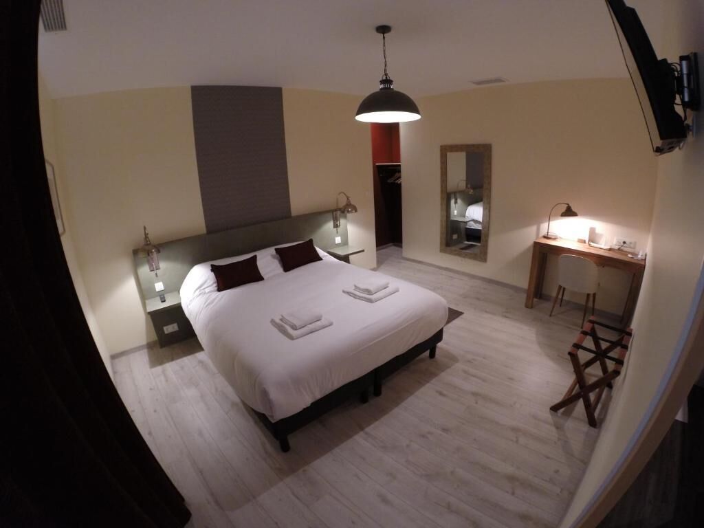 Ein Schlafzimmer mit Bett, Nachttischlampen, Schreibtisch und Spiegel.