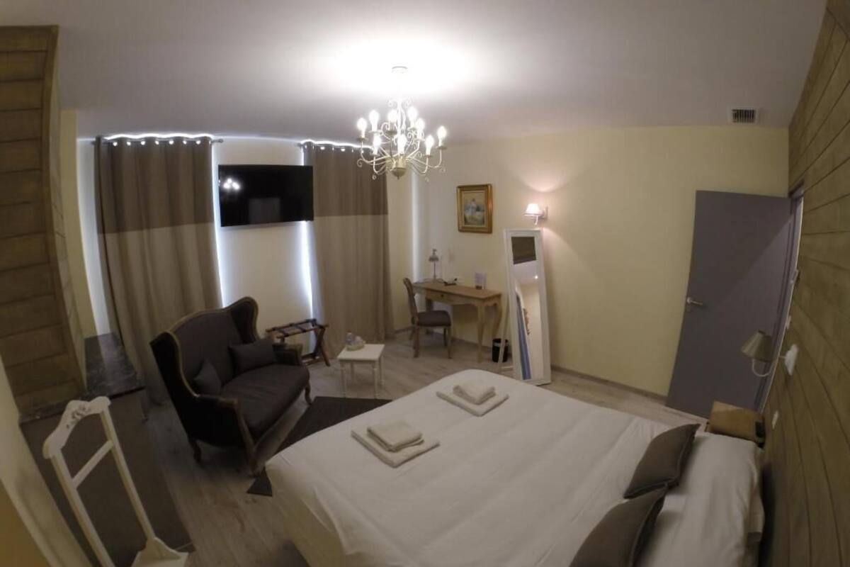 A hotel room with a bed, a desk, a chair, a sofa, and a TV.