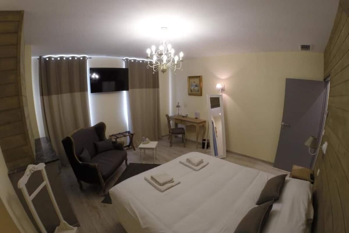 Une chambre d’hôtel comprenant un lit, un bureau, une chaise, un canapé et un téléviseur.