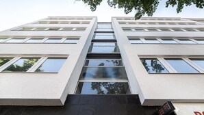 A modern building with a flat facade, numbered 34, featuring large windows and a digital clock displaying 26:26. - Greystay Apartments Steglitz (Berlin)