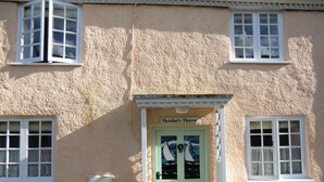 Ein Gebäude mit einer strukturierten Fassade, einer grünen Tür mit der Aufschrift „Heydon's House“ und zwei Fenstern mit weißen Rahmen.