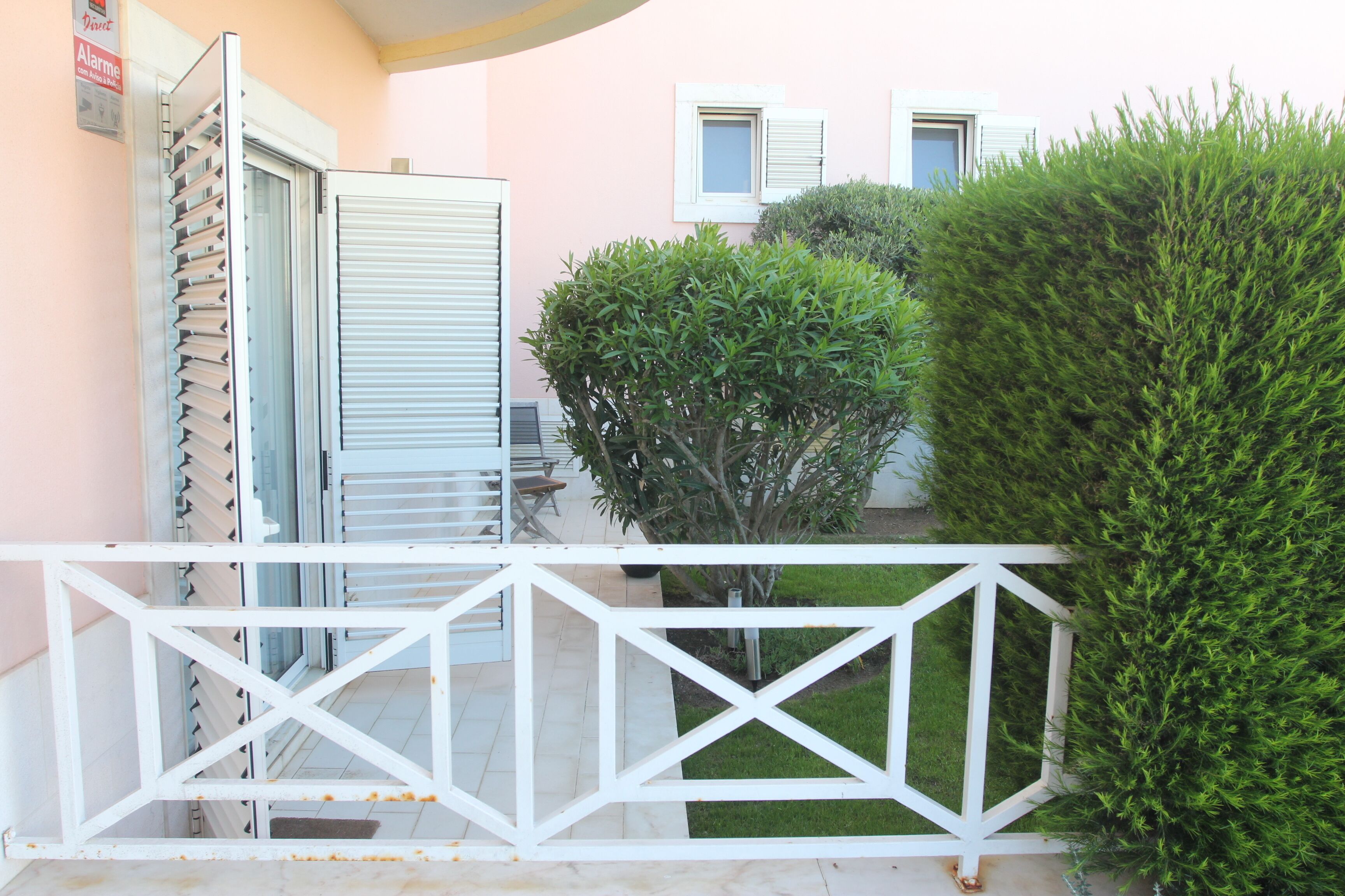 A balcony with a white railing, a small table, and a chair.