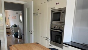Une cuisine moderne avec une table en bois et des chaises noires, des armoires blanches et des appareils électroménagers en acier inoxydable.