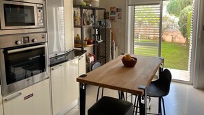 Une cuisine moderne équipée d’un four encastré, d’un micro-ondes et d’un coin repas avec une table et des chaises en bois.