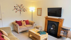 A living room with a sofa, a coffee table, a fireplace, and a television.