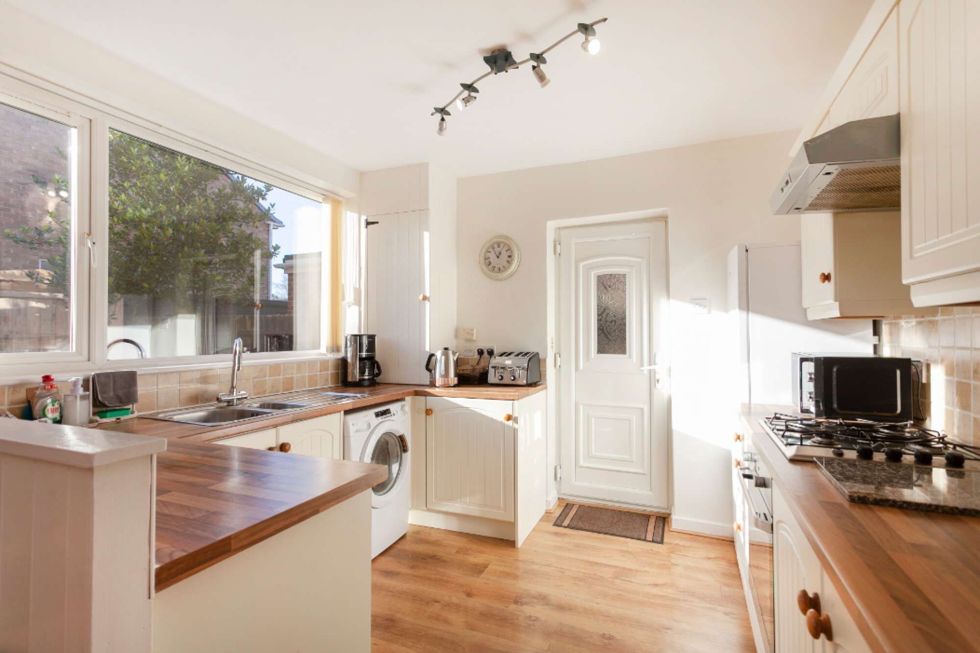 A kitchen with a washing machine, a stove, a microwave, and a toaster.