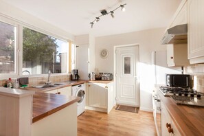 A kitchen with a washing machine, a stove, a microwave, and a toaster. - Lovely 4 bedroom detached house in Southwell (Southwell)