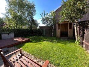 A backyard with a wooden deck, a grassy lawn, and a wooden fence. - Lovely 4 bedroom detached house in Southwell (Southwell)