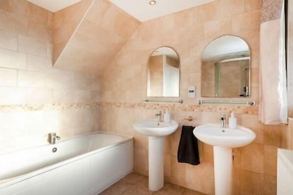 Ein Badezimmer mit einer Badewanne, zwei Waschbecken und zwei Spiegeln.