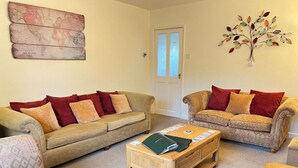 A living room with two sofas, a coffee table, and a decorative wall piece.