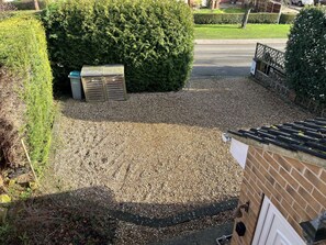 A gravel driveway leading to a wooden shed, surrounded by well-maintained hedges and a brick wall.