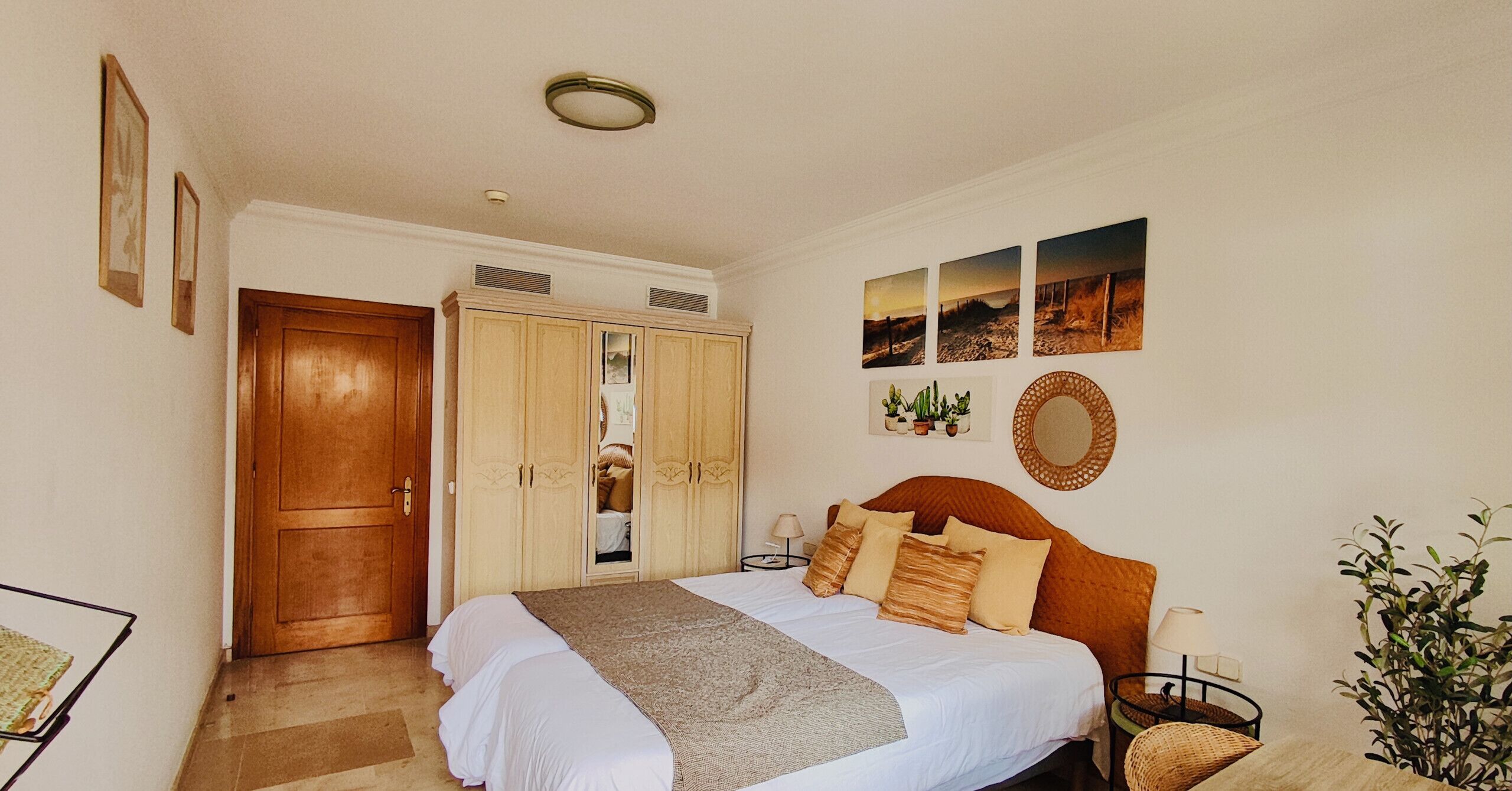 Un dormitorio con cama, armario, espejo y decoración en la pared.