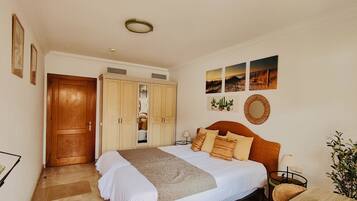 Un dormitorio con cama, armario, espejo y decoración en la pared.