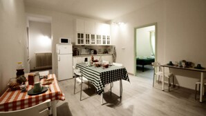 A compact kitchen with white cabinets, a microwave, and a dining area with a checkered tablecloth. - B&B La Rosa di Orvieto (Orvieto)