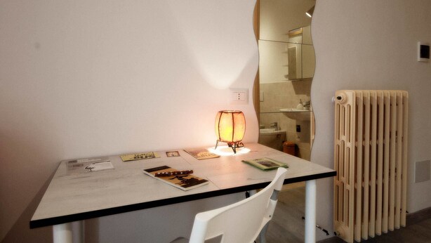 A small, modern room with a white table, a lamp, a chair, and a radiator. - B&B La Rosa di Orvieto (Orvieto)